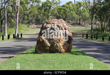 Large rock on a grassy area between two roads in a rural area Stock Photo