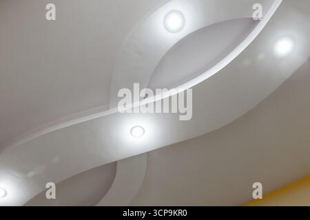 Soft, architectural curves and recessed lighting create a calm, minimalist modern interior. Clean lines and a sculptural ceiling form a serene, contem Stock Photo