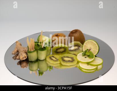 Close up shot of Kiwi, lemon, sliced ginger, ginger, lemon, mint leaves and cucumber taken on a mirror Stock Photo