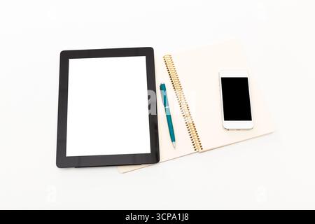 Workspace setup with tablet, notebook, pen, and smartphone displayed on white background Stock Photo