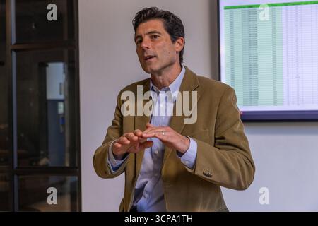 Man gesturing in conference room while presenting spreadsheet on monitor Stock Photo