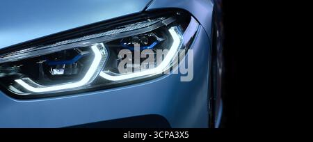 Close-up front headlight with xenon light of blue modern car on black color background and copy space Stock Photo