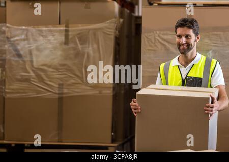 Cardboard boxes wrapped in clear plastic film are standing on metal racks in warehouse storage area Stock Photo