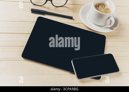 Modern workspace setup featuring coffee, tablet, and smartphone on wooden table Stock Photo