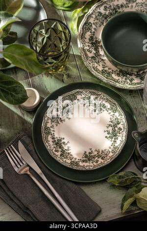 Beautiful table setting with different green rustik plates on wooden background in bright morning light. Vertical Stock Photo