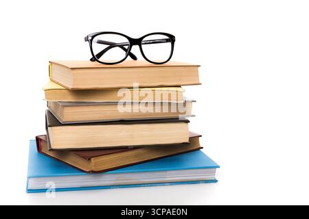 Stack of books with black eyeglasses on top against a white background Stock Photo