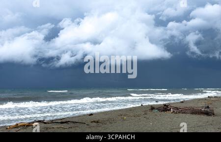 thunderstorm with heavy rain clouds and waves breaking on the beach Stock Photo