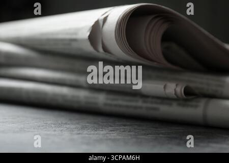 Stack of newspapers on grey table, closeup Stock Photo