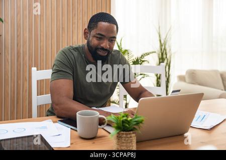 Young university student, freelancer business man, working at home on laptop computer, testing new innovative technology and online internet tools whi Stock Photo