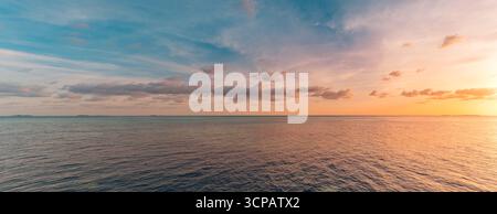 Picturesque panoramic colorful sunset over sea with glowing sky, dramatic clouds, radiant sun rays, dream peaceful nature background, inspire horizon Stock Photo