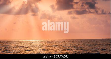 Fantastic golden sunset over calm sea with dramatic sky, soft clouds, and glowing sun rays dream peaceful nature background and tranquil seascape view Stock Photo