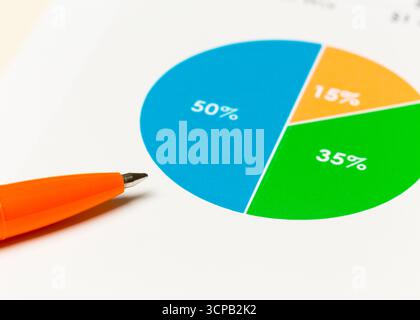 Detailed pie chart showing data distribution with orange pen for business analysis Stock Photo