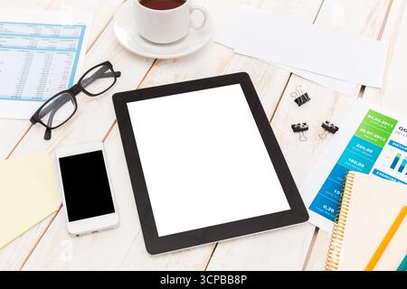 Office workspace with tablet, smartphone, coffee, and documents on wooden table Stock Photo