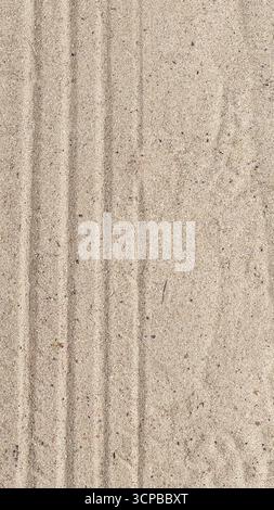 Close-up of textured sand with visible lines and patterns. The surface appears smooth and light beige in color, showcasing natural elements. Stock Photo