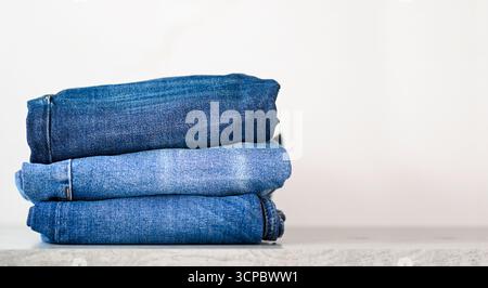 Stack of blue jeans on a shelf, space for text Stock Photo