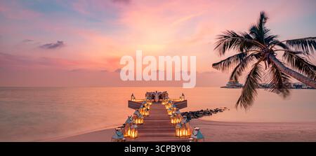 Panoramic romantic dinner table candles pier palm trees sea view background. Love couple honeymoon anniversary luxury destination dining Stock Photo