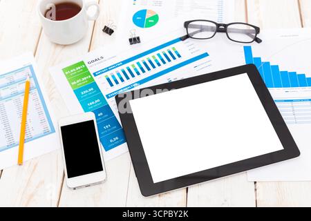 Office workspace displaying tablet, smartphone, documents, and coffee cup during work hours Stock Photo