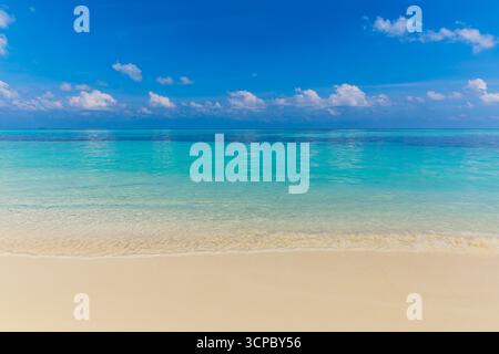 Calm tropical beach landscape at sunrise with soft sand, gentle sea waves, and a serene sky with wispy clouds creating a peaceful holiday scene. Stock Photo