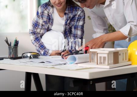 Engineer collaborating on architectural plans and model construction Stock Photo