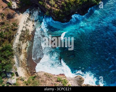 Aerial view of waves crashing against the rocky coastline and sandy ...