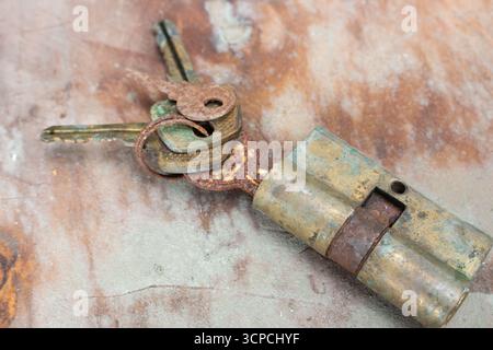 Old rusty keys in lock. Vintage door padlock with keys. Antique keys on weathered background with copy space. Security and safety concept. Stock Photo