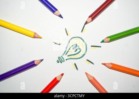 Creative Idea Concept with Colorful Pencils Pointing to a Hand Drawn Glowing Light Bulb on White Background Stock Photo