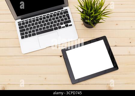 Stylish workspace with laptop and tablet on wooden desk featuring a small plant Stock Photo