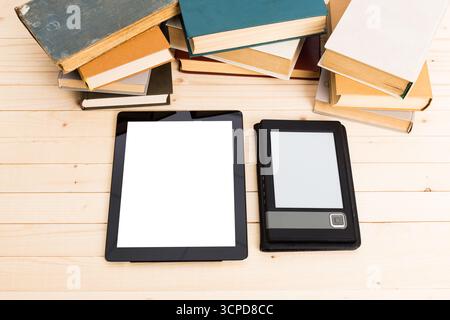 Digital devices alongside stacked books on a wooden surface in a study environment Stock Photo