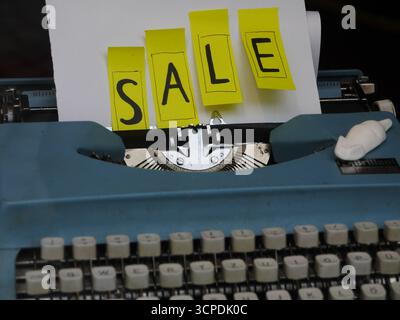 Blue typewriter with yellow sticky notes on it that say Sale Stock Photo