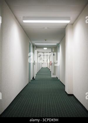 Long hallway with a green carpet and white walls Stock Photo