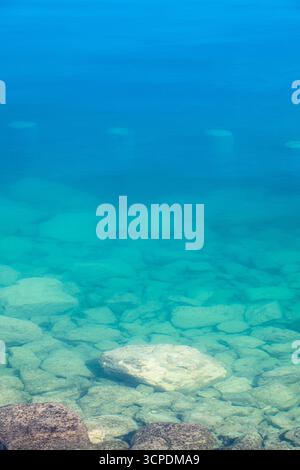 Stones, pebbel and concrete poles under the transparent blue water of the lake sea Stock Photo