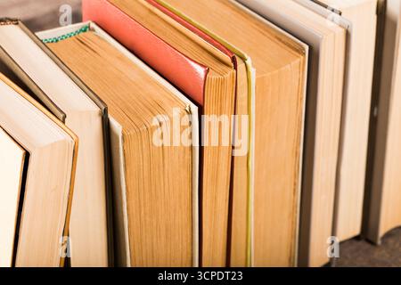 Stack of various hardcover books on a wooden surface in soft natural light Stock Photo