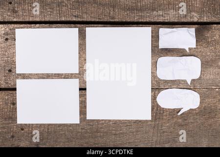 Blank paper and speech bubbles arranged on a rustic wooden surface for creative use Stock Photo