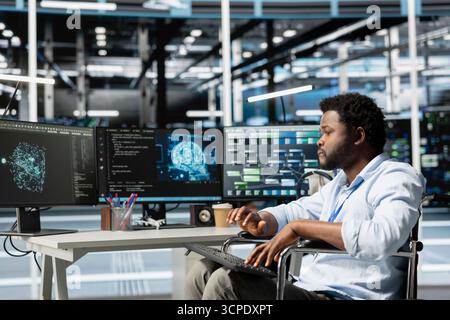 Data center engineer with disability in wheelchair using AI visualization tool. Worker with paraplegia in inclusive server farm workplace uses artificial intelligence analysis software Stock Photo