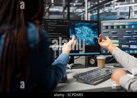 Data center engineer and colleague use artificial intelligence neural networks technology. Teamworking employees doing brainstorming in server room, using AI programming language to configure hardware Stock Photo