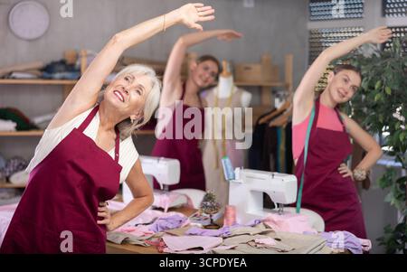 team of dressmakers doing a warm-up in the workshop Stock Photo
