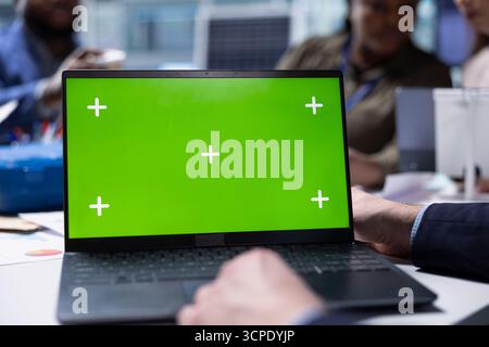 Factory manager preparing for investors visit, using green screen laptop to write manufacturing strategies data documentation. Man types on chroma key notebook, preparing report for shareholders Stock Photo