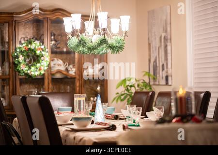 Festive table setting during Christmas Holidays with candle light and xmas wreath. Stock Photo