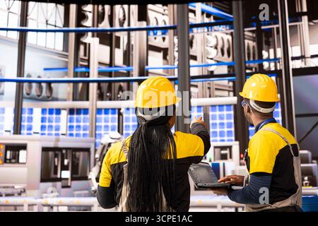 Advanced manufacturing specialists overseeing maintenance of high tech automation line, robotic arms and conveyor belts. Professional engineers working on solar panels production in smart factory. Stock Photo