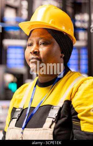 Female engineer in industrial facility, monitoring system performance and ensuring safety. African American woman overseeing production of innovative devices in high tech manufacturing plant. Stock Photo