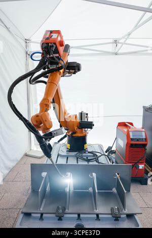 Industrial robot is welding metal part. Stock Photo