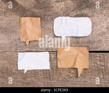 Empty speech bubbles on crumpled paper backgrounds on wooden surface Stock Photo