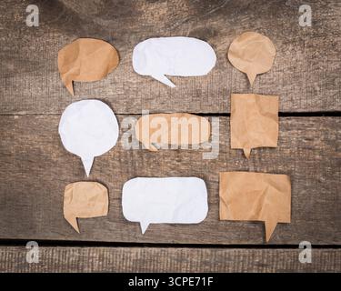 Creative paper speech bubbles arranged on rustic wooden background for communication display Stock Photo