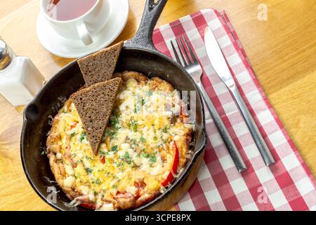 Delicious breakfast served in skillet with bread on checkered tablecloth Stock Photo