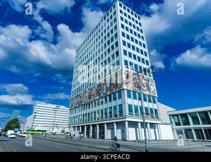 Wide shot of Haus des Lehrers (house of the teacher) with famous mural frieze and bright blue summer sky, located at Alexanderplatz in Berlin Mitte. Stock Photo