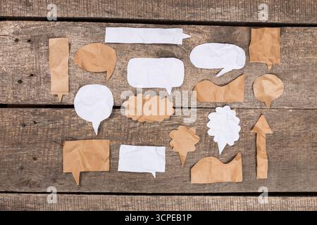 Collection of speech bubble cutouts arranged on a rustic wooden surface Stock Photo