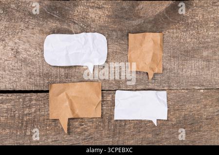 Messaging bubbles made from crumpled paper on wooden surface Stock Photo