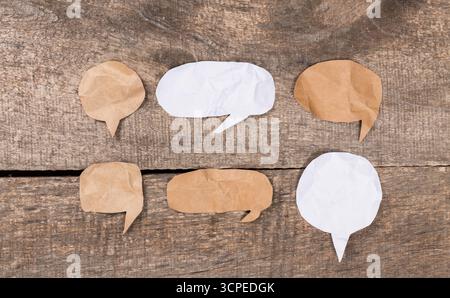 Various crumpled paper speech bubbles arranged on a wooden surface Stock Photo