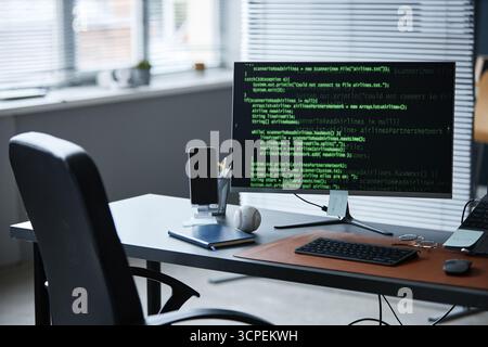 Modern Office Desk Featuring Smartphone and Baseball Beside Coding Monitor Stock Photo