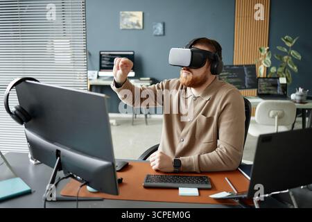 Young Adult Man Using Virtual Reality Headset While Working Stock Photo
